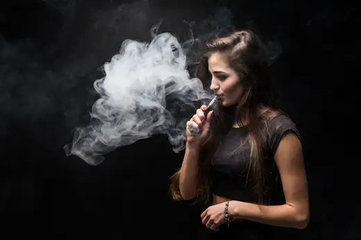sexy girl black dress smoking electronic cigarette dark wall